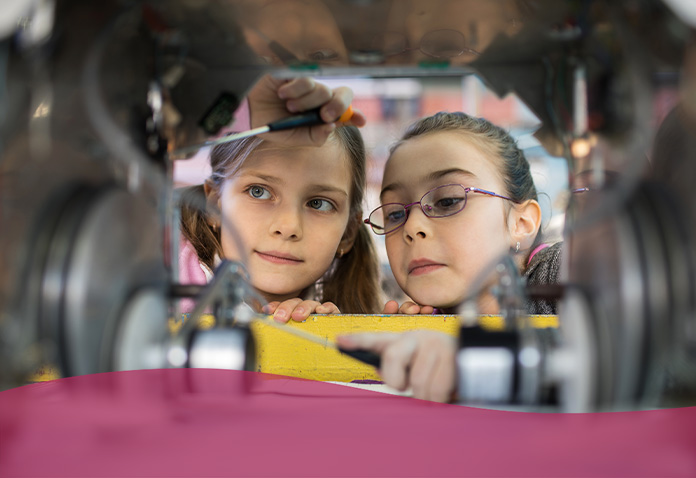 Two elementary female students work on a robot together