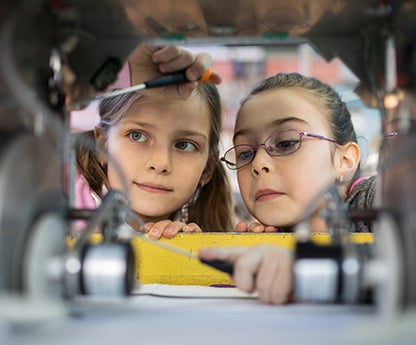 Two female elementary students work on a robot