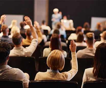 A group of people at DLAC - raising their hands to discuss online learning in the K-12 space.