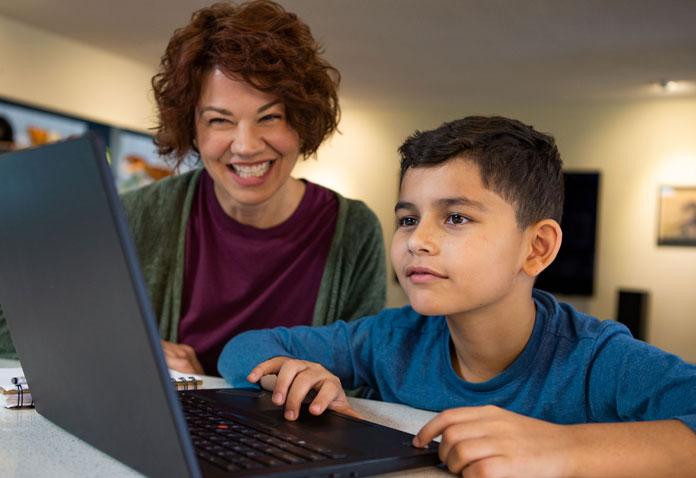 Woman helping boy using computer