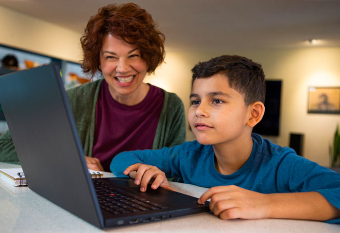 Woman helping boy using computer